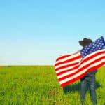 Leben USA - Green Card Lorrerie - Titlebild - Mann mit USA Fahne auf dem Feld